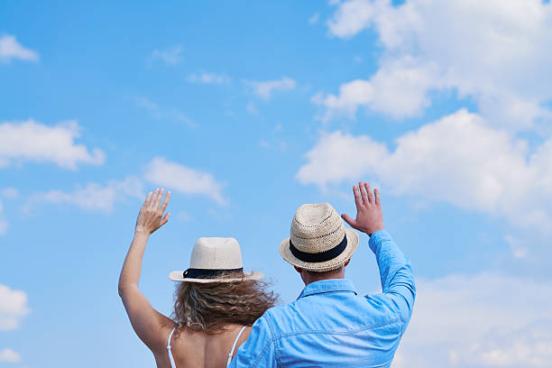 Back view of couple waving hands to the sky